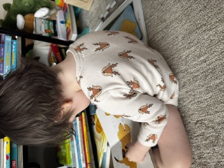 A toddler sitting on the floor absorbed in a book.
